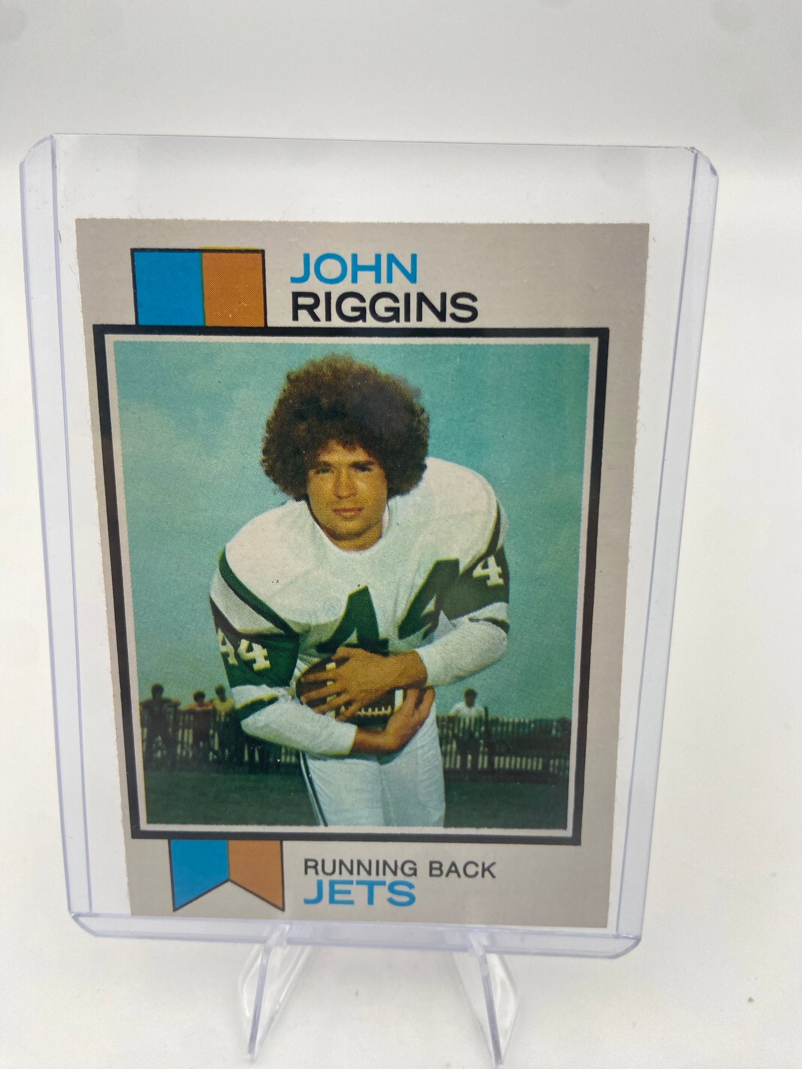 1973 Topps John Riggins Jets Rookie Card: This is a 1973 Topps football card featuring Hall of Fame running back John Riggins in his early career with the New York Jets. The card is encased in a protective plastic top loader. It shows