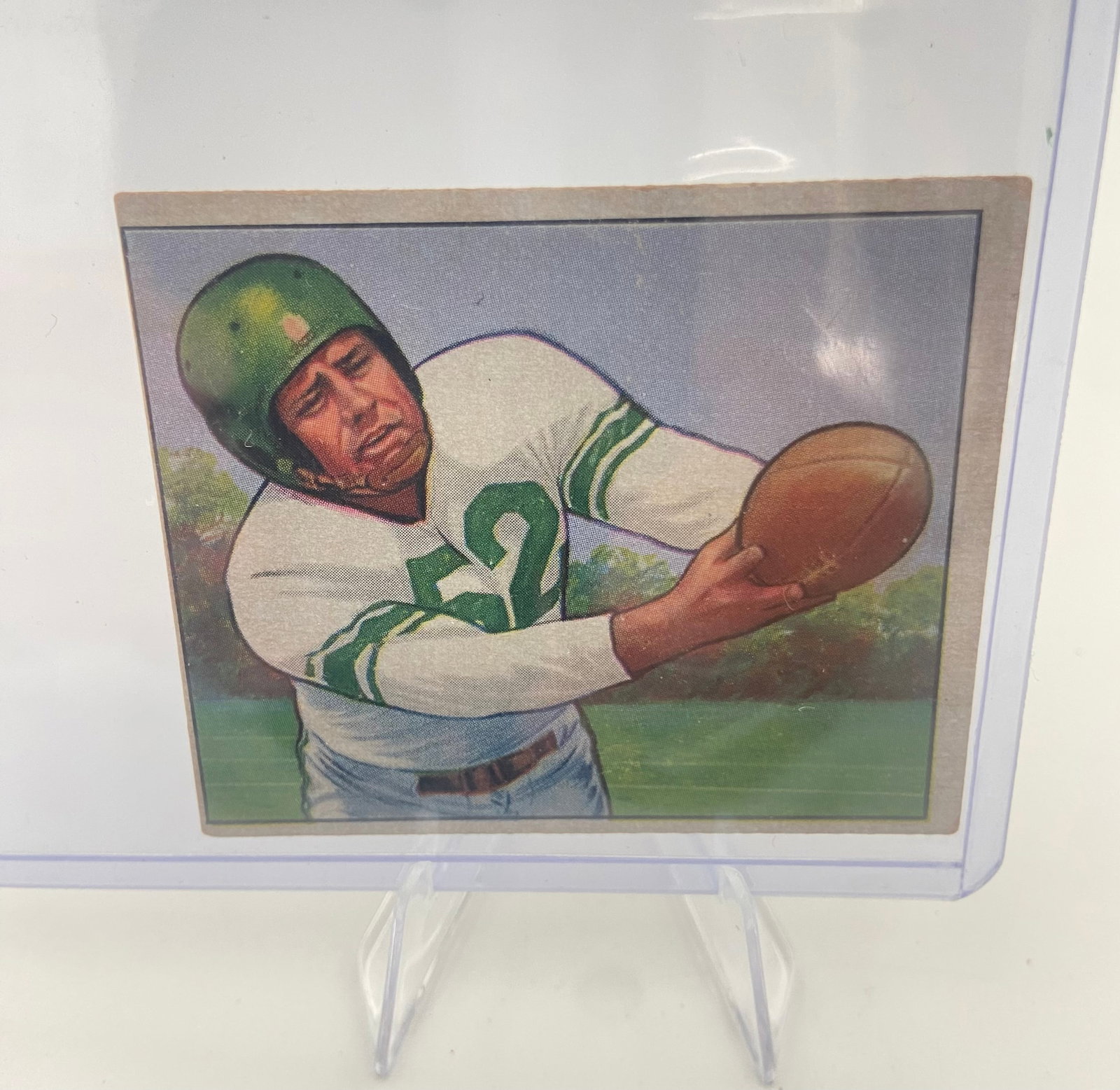 1948 Leaf Football Card: This is a vintage 1948 Leaf football card featuring an illustrated action shot of a player wearing a green helmet and jersey number 52. The card is protected in a clear rigid plastic sleeve. These ear