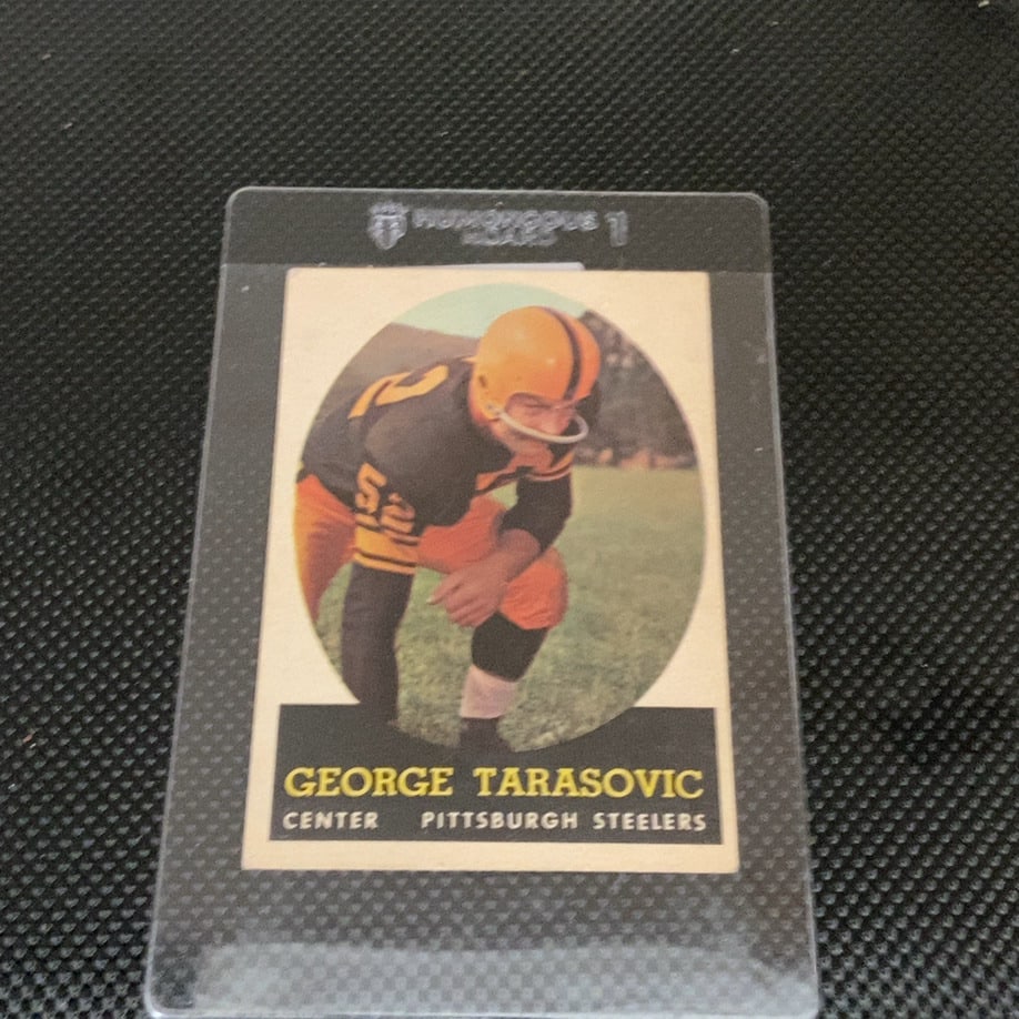 1961 Topps George Tarasovic Pittsburgh Steelers Card: This is a 1961 Topps football trading card featuring George Tarasovic of the Pittsburgh Steelers. The card shows him in his center position gear and is preserved in a protective Humongous Board
