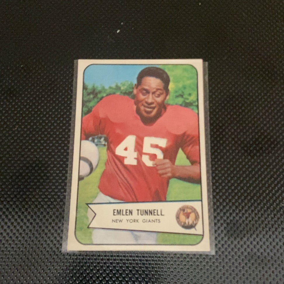 1960 Topps Emlen Tunnell New York Giants Football Card: This is a 1960 Topps football card featuring Pro Football Hall of Famer Emlen Tunnell of the New York Giants. The card shows Tunnell in his red jersey and is encapsulated in a protective sleeve.
