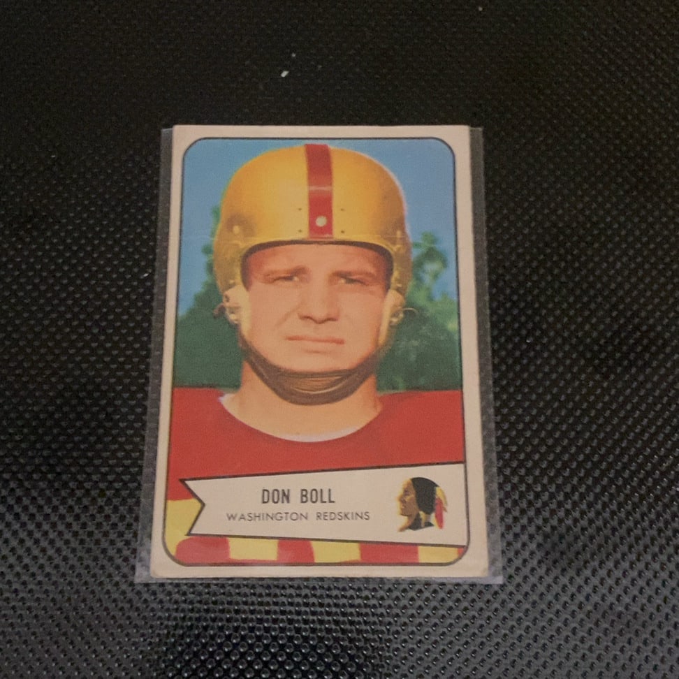 1957 Topps Don Boll Washington Redskins Football Card: This is a 1957 Topps football card featuring Don Boll of the Washington Redskins. The card displays a portrait of the player and is enclosed in a protective plastic sleeve, showing signs of vintage