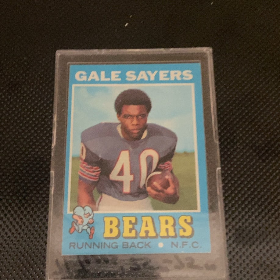 1971 Topps Gale Sayers Chicago Bears Football Card: This is a 1971 Topps football card featuring Chicago Bears running back Gale Sayers. The card is enclosed in a hard plastic protective case and displays vibrant colors with the iconic Bears logo in