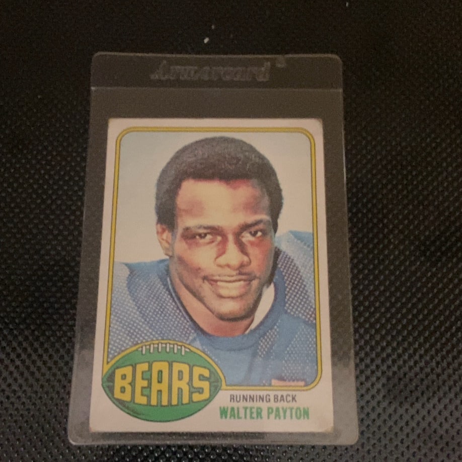 1976 Topps Walter Payton Rookie Football Card: This is a 1976 Topps football card featuring legendary Chicago Bears running back Walter Payton. The card is encased in a protective Armarcard plastic sleeve and appears to be in overall good