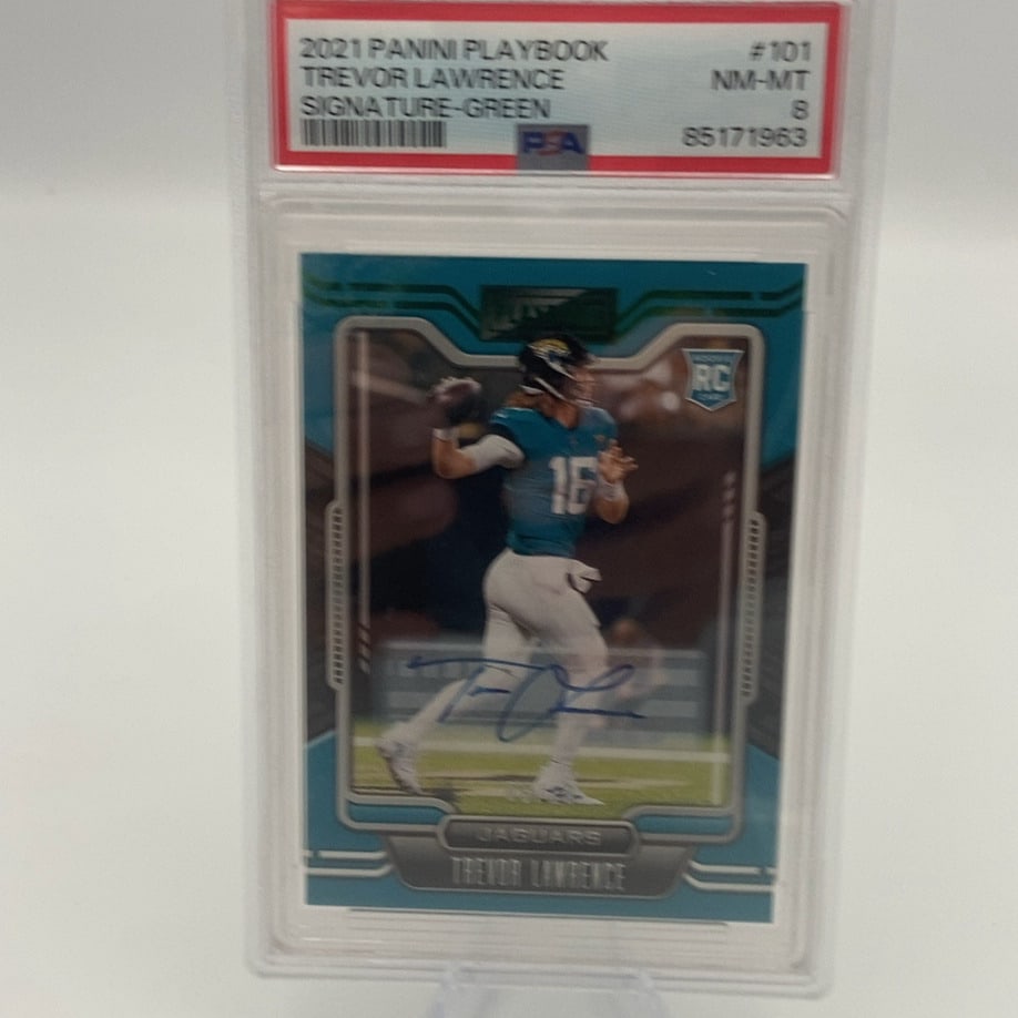 2021 Panini Playbook Trevor Lawrence: This is a 2021 Panini Playbook trading card featuring Trevor Lawrence of the Jacksonville Jaguars. The card is a Signature Green edition and has been professionally graded by PSA as a NM-MT 8. It
