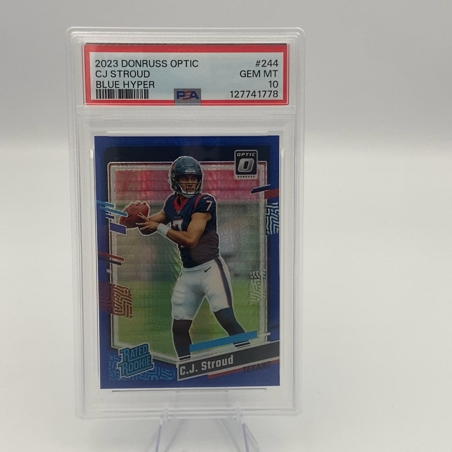 2023 Donruss Optic CJ Stroud: This is a 2023 Donruss Optic Rated Rookie football card featuring CJ Stroud. The card is a Blue Hyper parallel version that has been graded GEM MT 10 by PSA.