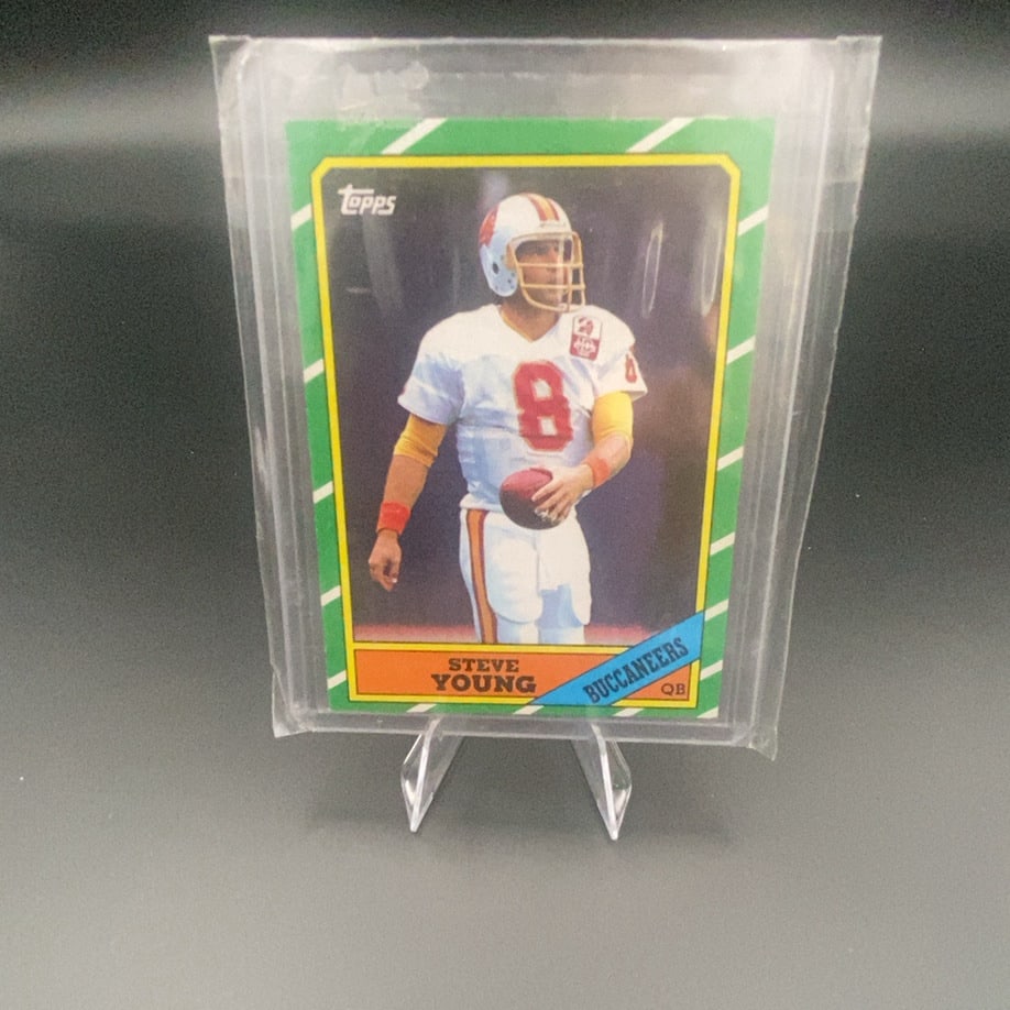 1986 Topps Steve Young: This is a 1986 Topps football card featuring Steve Young in his Tampa Bay Buccaneers uniform. The card includes the iconic Topps logo in the upper left corner and the player's name and team printed