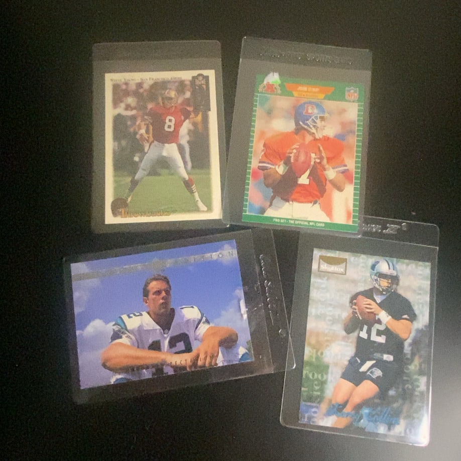 Vintage NFL Football Trading Card Collection (4 Cards): This lot features a collection of four vintage NFL football trading cards. The visible cards include Steve Young, John Elway, and Kerry Collins, produced by brands such as Pro Set and SkyBox.