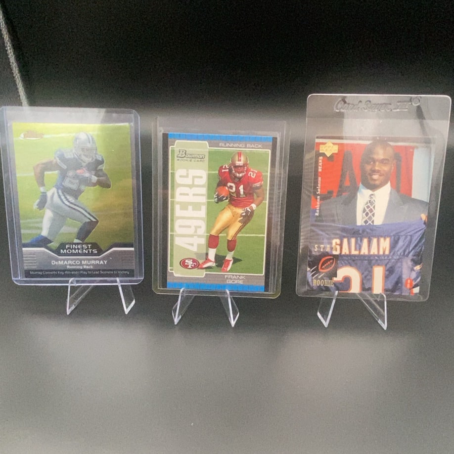 2005 Bowman Frank Gore Rookie Card: This is a 2005 Bowman Frank Gore rookie card featured in the middle of a protective display case alongside other football cards. The card highlights Frank Gore, identified as a Running Back for the