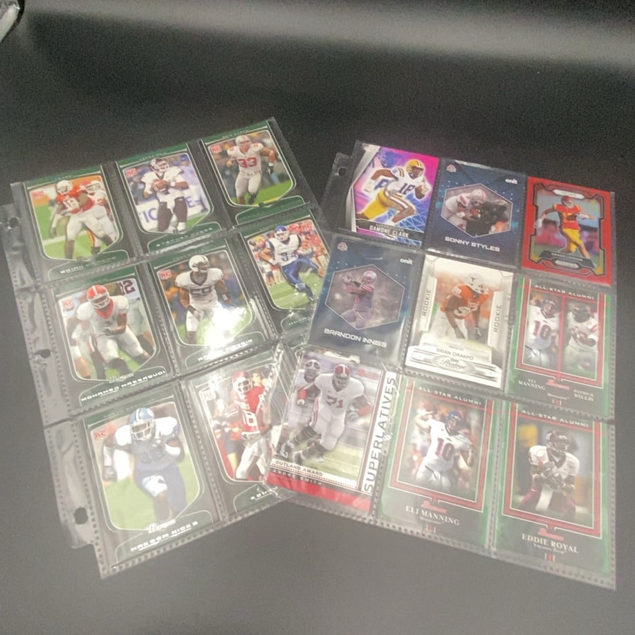 Assorted Football Trading Cards Lot: This image features a collection of various football trading cards housed in a protective plastic binder sheet. The collection includes rookie cards, All-Star alumni cards, and various players such