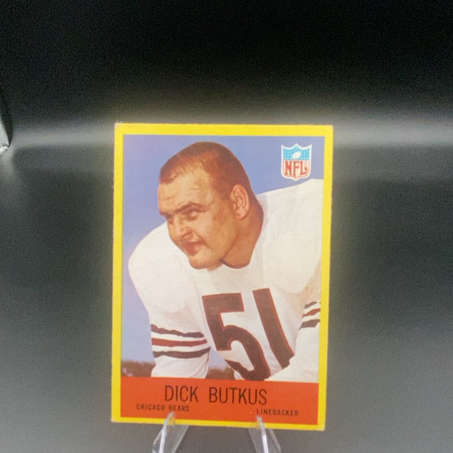 Dick Butkus Chicago Bears Football Card: This is a vintage trading card featuring Dick Butkus of the Chicago Bears. The card displays him in his jersey with the number 51 and includes the official NFL logo. The design features a distinctive