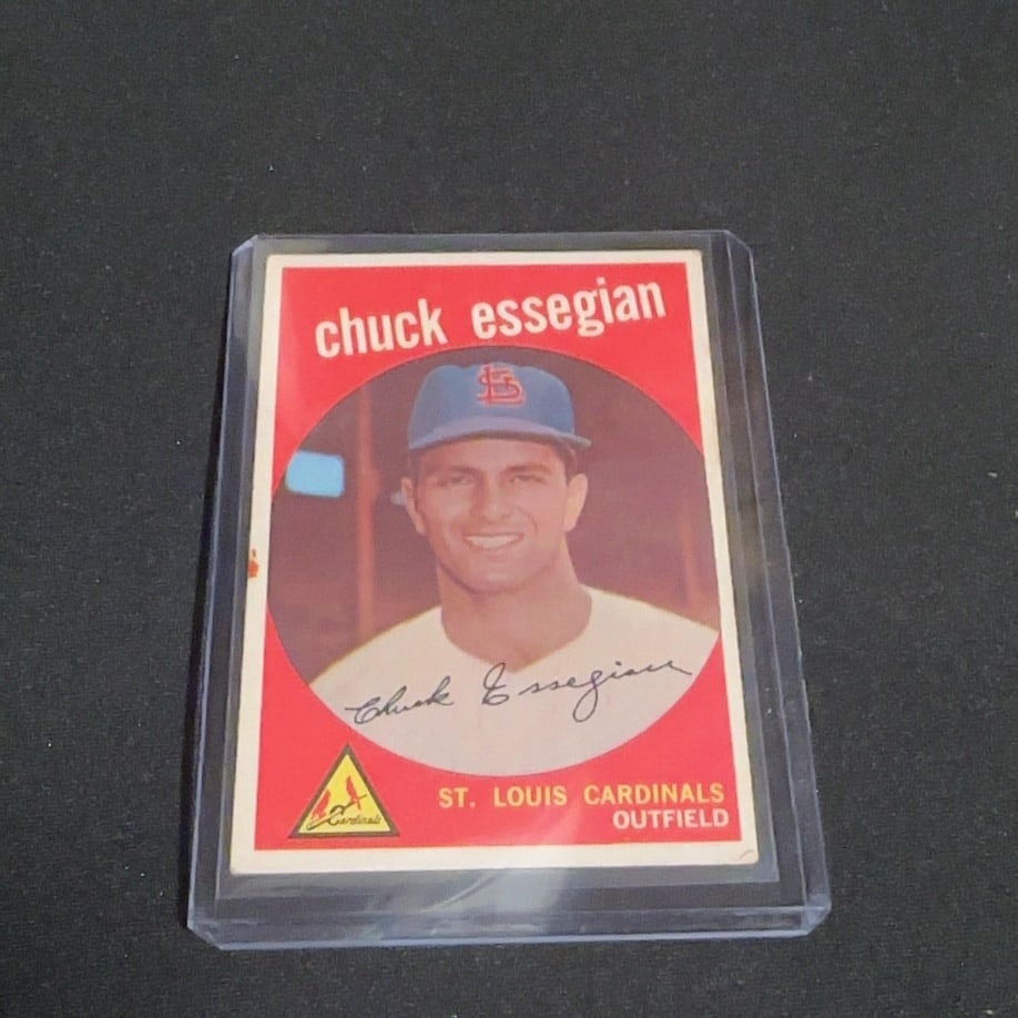 1961 Topps Chuck Essegian Baseball Card: This is a 1961 Topps baseball card featuring St. Louis Cardinals outfielder Chuck Essegian. The card is encased in a protective plastic sleeve and displays a vibrant red background with a portrait of 