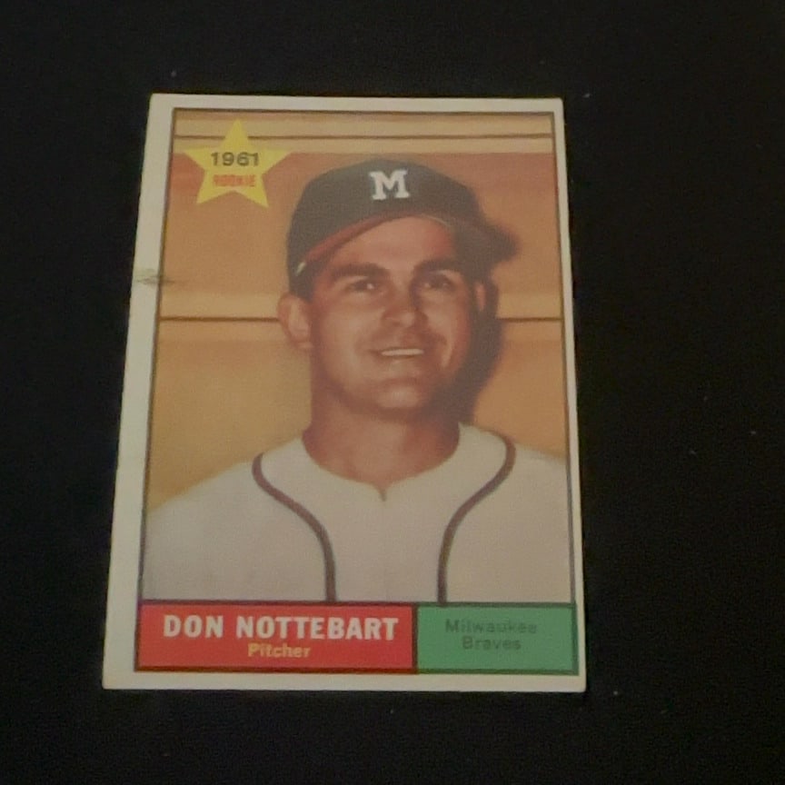 1961 Topps Don Nottebart: This is a 1961 Topps baseball card featuring Milwaukee Braves pitcher Don Nottebart. The card highlights his status as a rookie with a star graphic on the upper left.