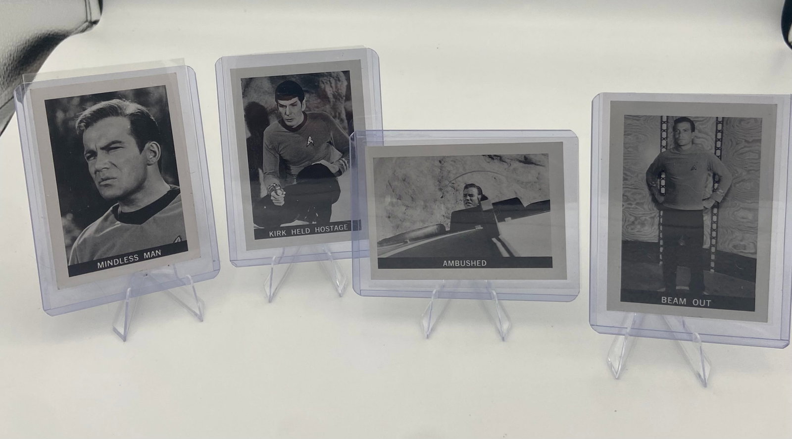 Vintage Star Trek B&W Trading Card Set: This lot includes a set of vintage black and white Star Trek trading cards featuring various scene captions like Mindless Man, Kirk Held Hostage, Ambushed, and Beam Out. Each card is protected in a