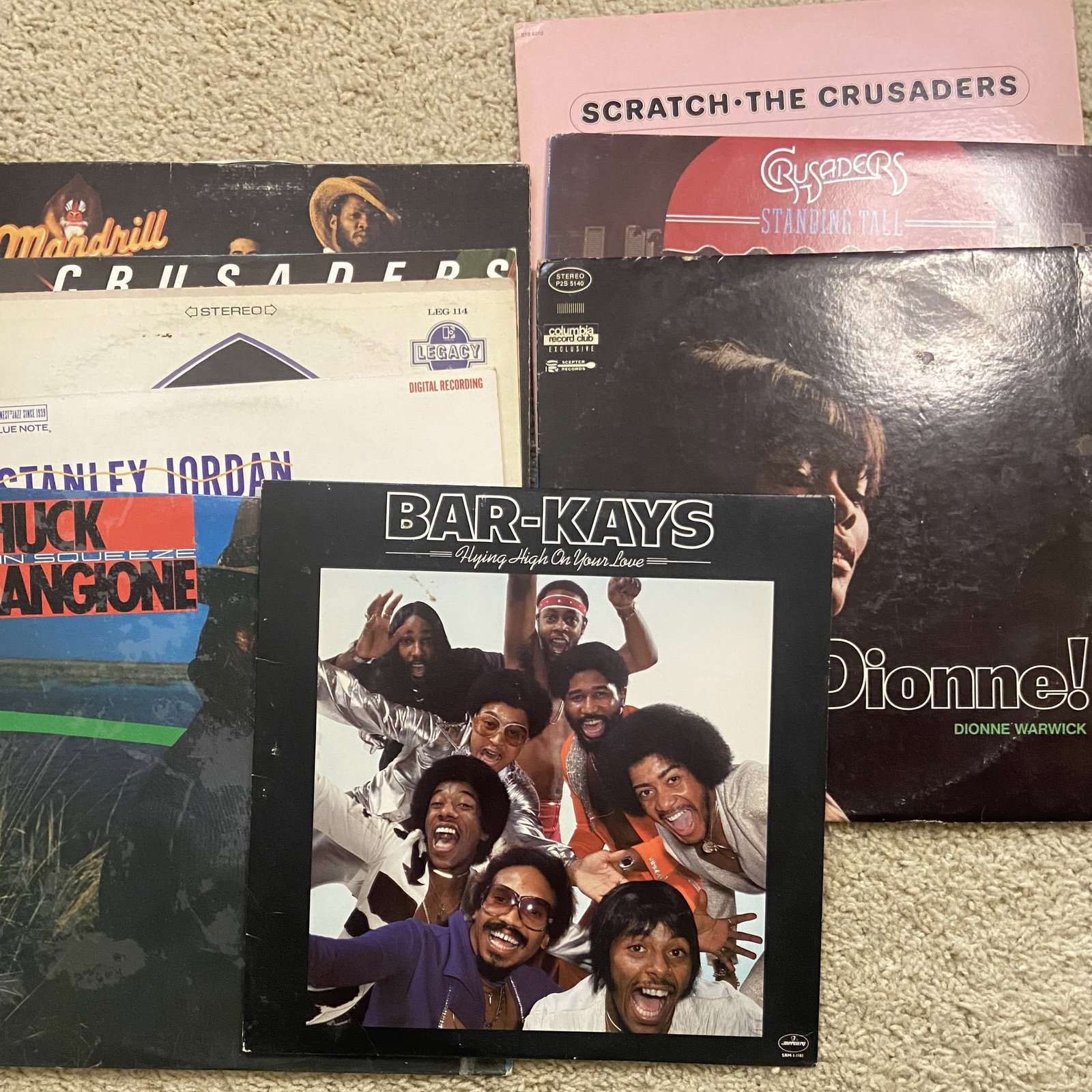 Collection of Vintage Vinyl Records: This is a collection of various vintage music vinyl record albums. Featured titles include Bar-Kays Flying High On Your Love, Dionne Warwick, Mandrill, and The Crusaders. These records represent