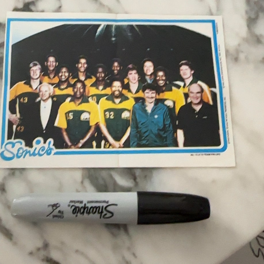 Seattle SuperSonics Team Photo: This is a vintage photographic collectible depicting the Seattle SuperSonics basketball team, with the team name printed clearly in the bottom left corner. The image captures a group team portrait fea