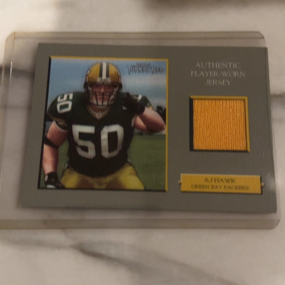 2006 Topps Turkey Red AJ Hawk Jersey Relic Card: This is a 2006 Topps Turkey Red football trading card featuring linebacker AJ Hawk of the Green Bay Packers. The card includes an embedded piece of an authentic player-worn jersey relic.