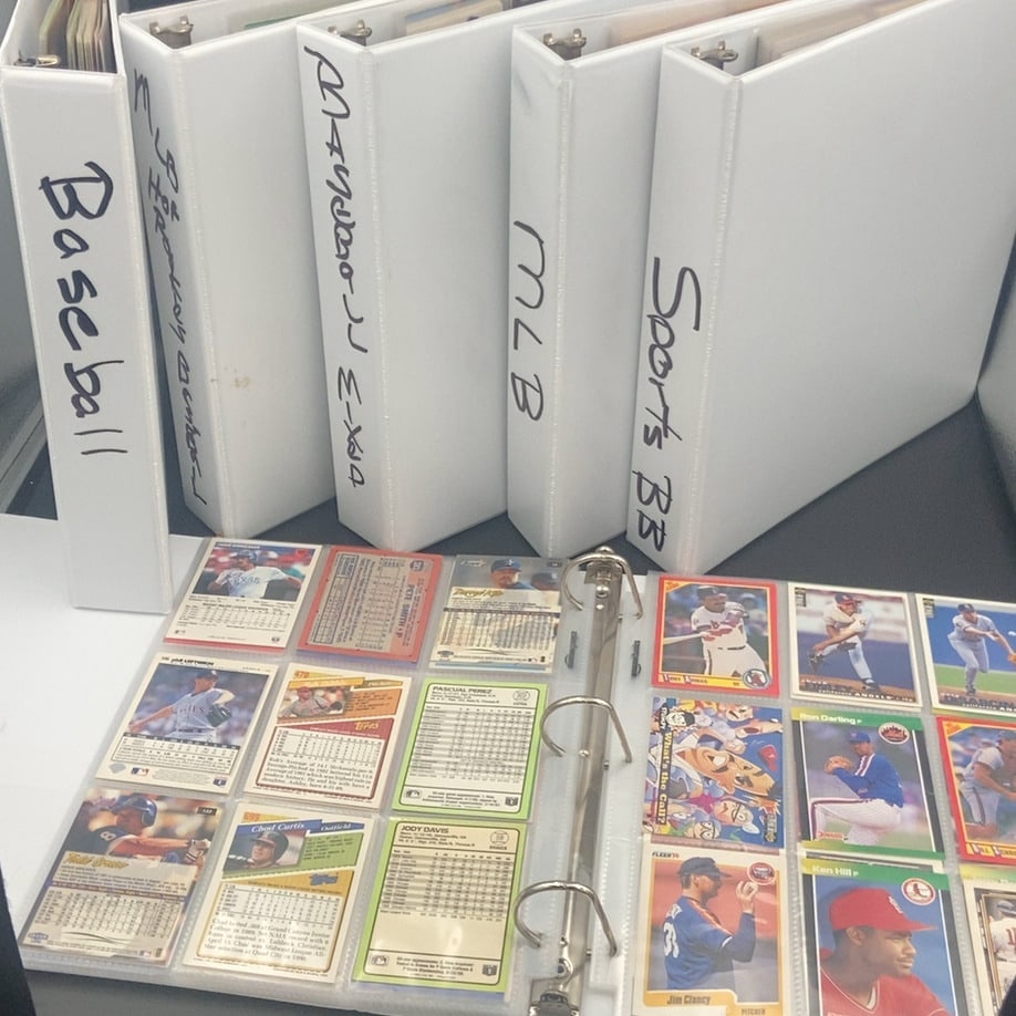 Assorted Sports Card Binders: lot features six white ring binders labeled with various categories like Baseball and MLB. Inside the open binder, there is an assortment of vintage baseball cards displayed in plastic pocket pages,