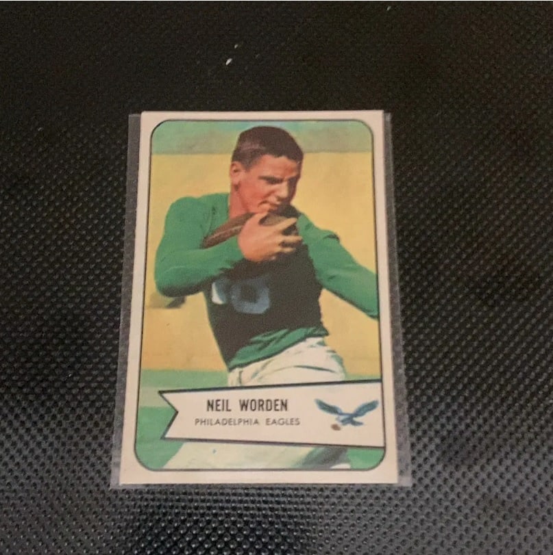 1959 Topps Neil Worden Philadelphia Eagles Football Card: This is a 1959 Topps football card featuring Philadelphia Eagles player Neil Worden. The card is encased in a protective sleeve and displays his name and team affiliation in a ribbon graphic at the bo