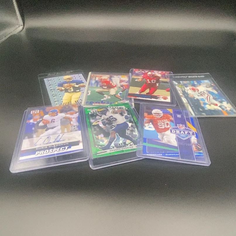Assorted Football Trading Cards Lot: This lot features a collection of assorted American football trading cards from various sets and manufacturers. The selection includes cards featuring players such as Chris Oladokun, Hassan Haskins,