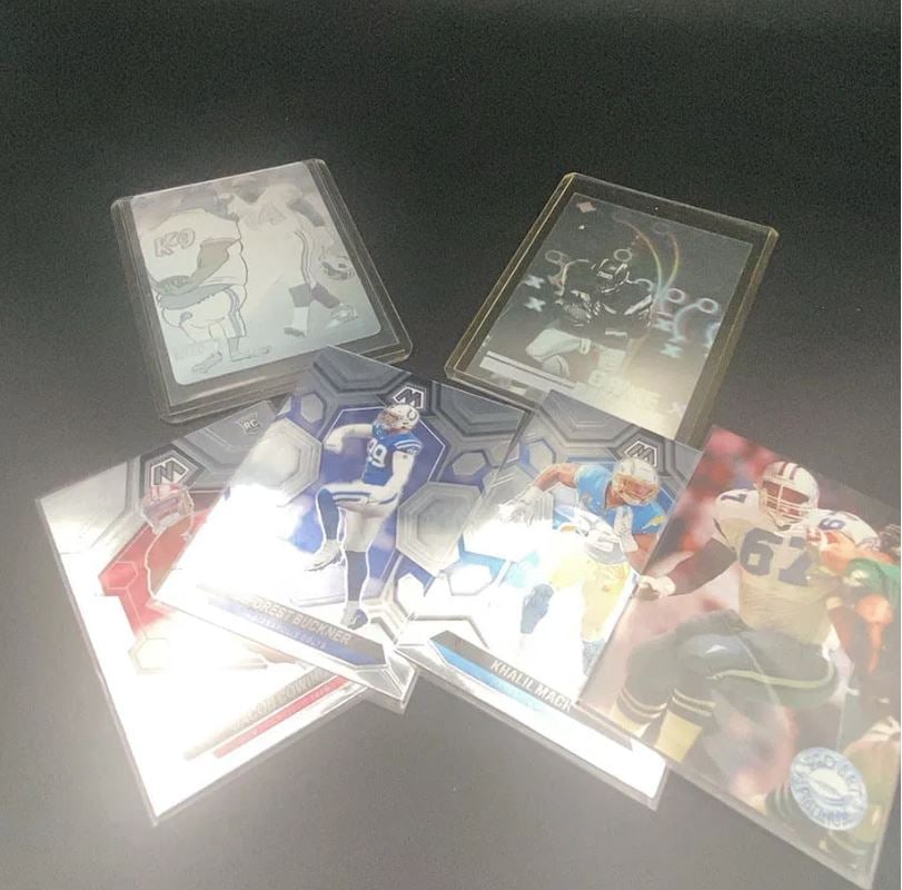 Assorted Football Trading Cards: This lot features a collection of assorted football trading cards, including several Panini Mosaic cards featuring players like DeForest Buckner and Khalil Mack. Other visible cards include a Jacob