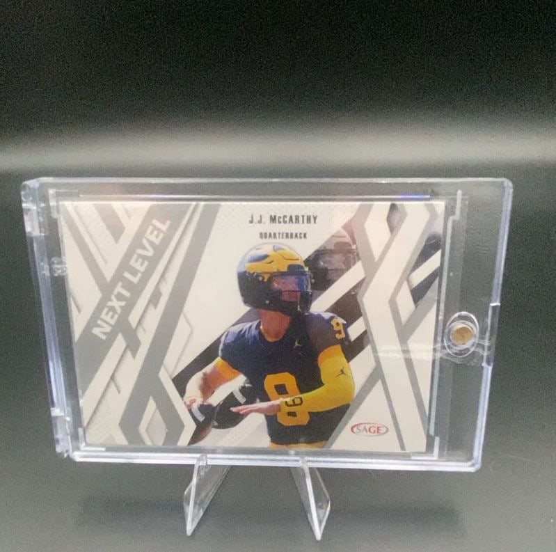 J.J. McCarthy Next Level: This is a trading card featuring J.J. McCarthy in his University of Michigan uniform, positioned as a Quarterback. The card is labeled 'NEXT LEVEL' and was produced by SAGE. It is encased in a