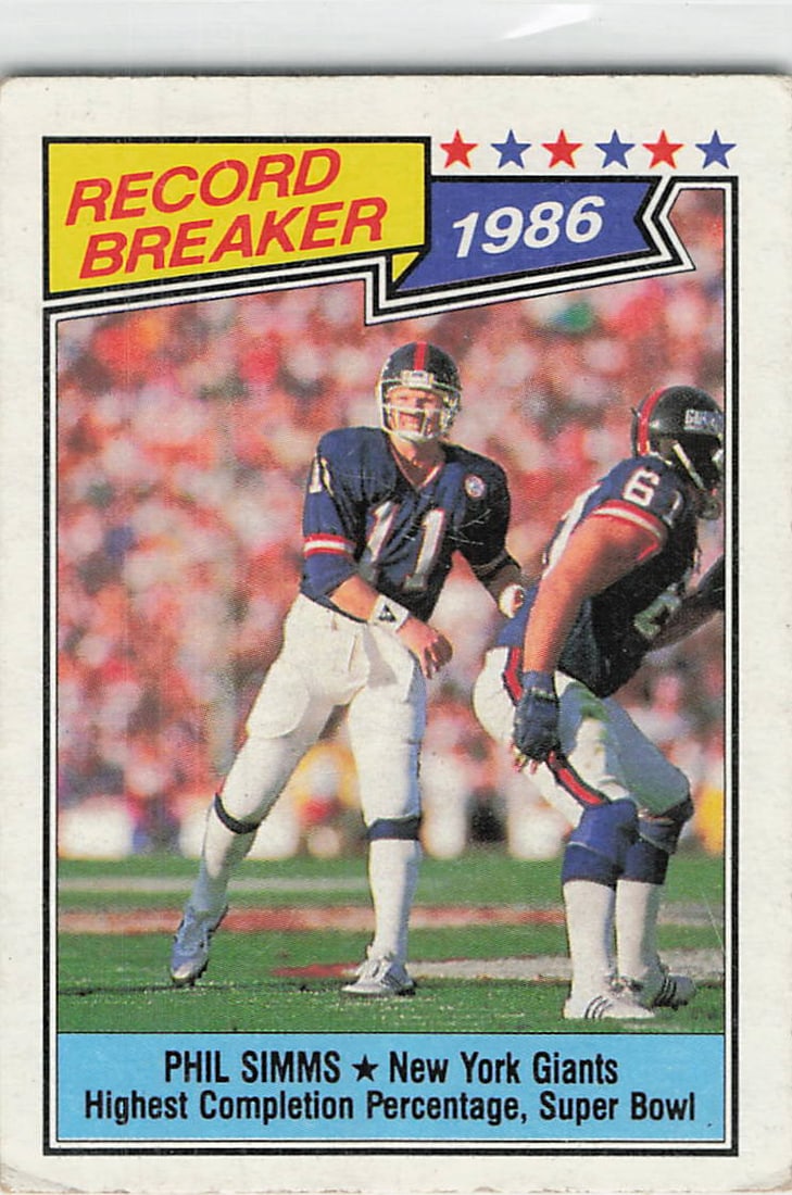 1987 Topps Phil Simms Record Breaker Football Card: This is a 1987 Topps football card featuring New York Giants quarterback Phil Simms, designated as a 'Record Breaker' for his performance in Super Bowl XXI. The card highlights his achievement of the