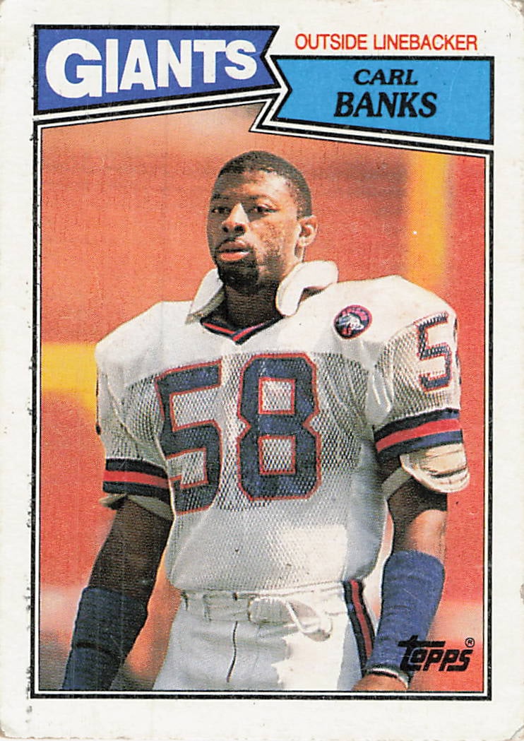 1987 Topps Carl Banks New York Giants Football Card: This is a 1987 Topps football card featuring New York Giants outside linebacker Carl Banks. The card identifies him by position and team with bold graphics characteristic of the 1985 set design. The