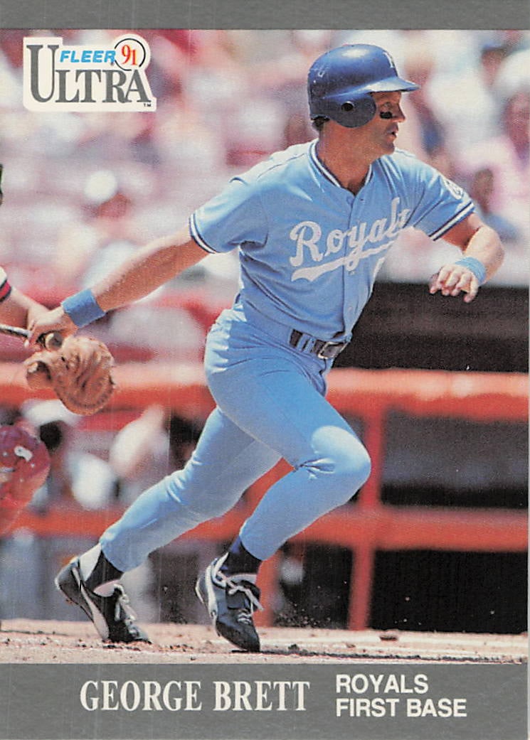 1991 Fleer Ultra George Brett Baseball Card: This is a 1991 Fleer Ultra baseball card featuring Hall of Famer George Brett of the Kansas City Royals. The card showcases action photography of Brett playing first base, reflecting the early design 
