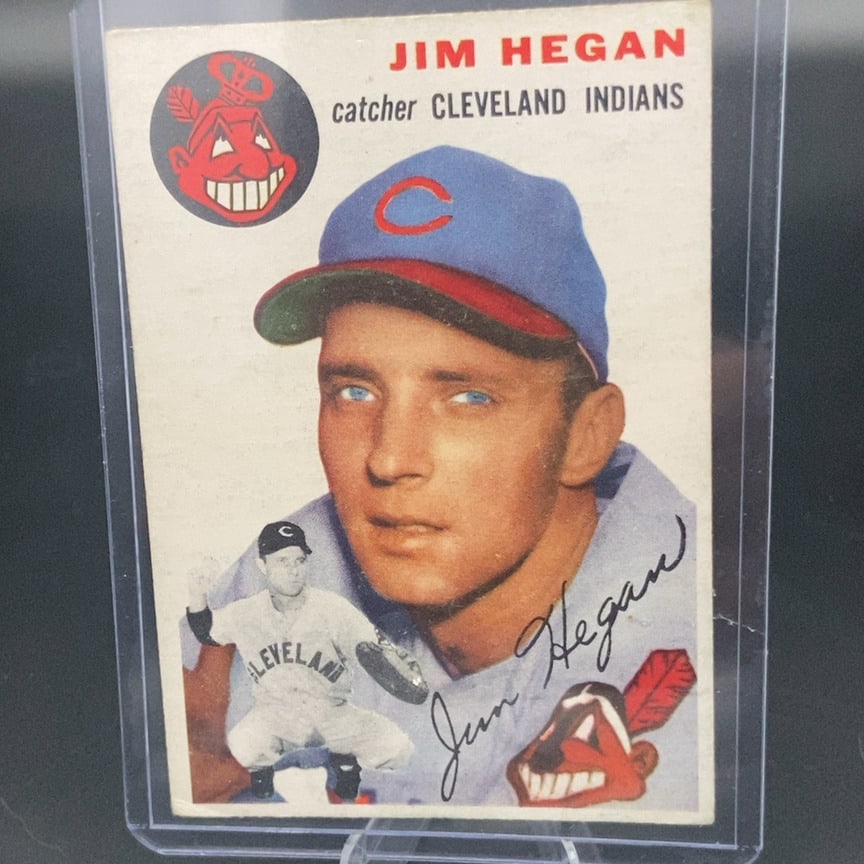 1954 Topps Jim Hegan Cleveland Indians Baseball Card: This is a 1954 Topps baseball card featuring Cleveland Indians catcher Jim Hegan. The card is enclosed in a protective plastic top loader and shows the player in a portrait style with a small action