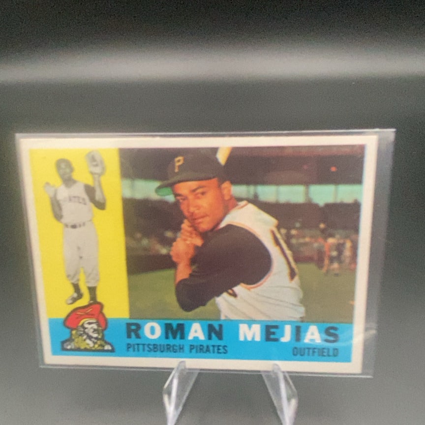 1960 Topps #2 Román Mejías baseball card: This is a vintage baseball card featuring outfielder Roman Mejias of the Pittsburgh Pirates. The card includes a portrait of the player and a small graphic of a pirate mascot on the front.