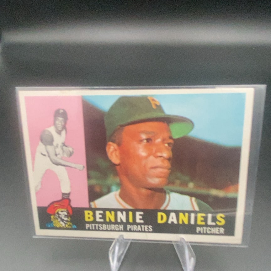 1960 Topps Bennie Daniels #91 baseball card: This is a 1960 Topps baseball card featuring Pittsburgh Pirates pitcher Bennie Daniels. The card features a portrait of the player alongside a smaller action image in a pink box and includes the team