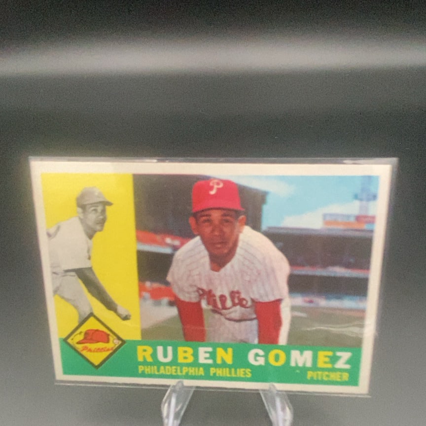 1960 Topps #82 Rubén Gómez baseball trading card: This is a vintage baseball card featuring Philadelphia Phillies pitcher Ruben Gomez. The card showcases a dual-image design with a close-up portrait and an action-style shot of the player on a green