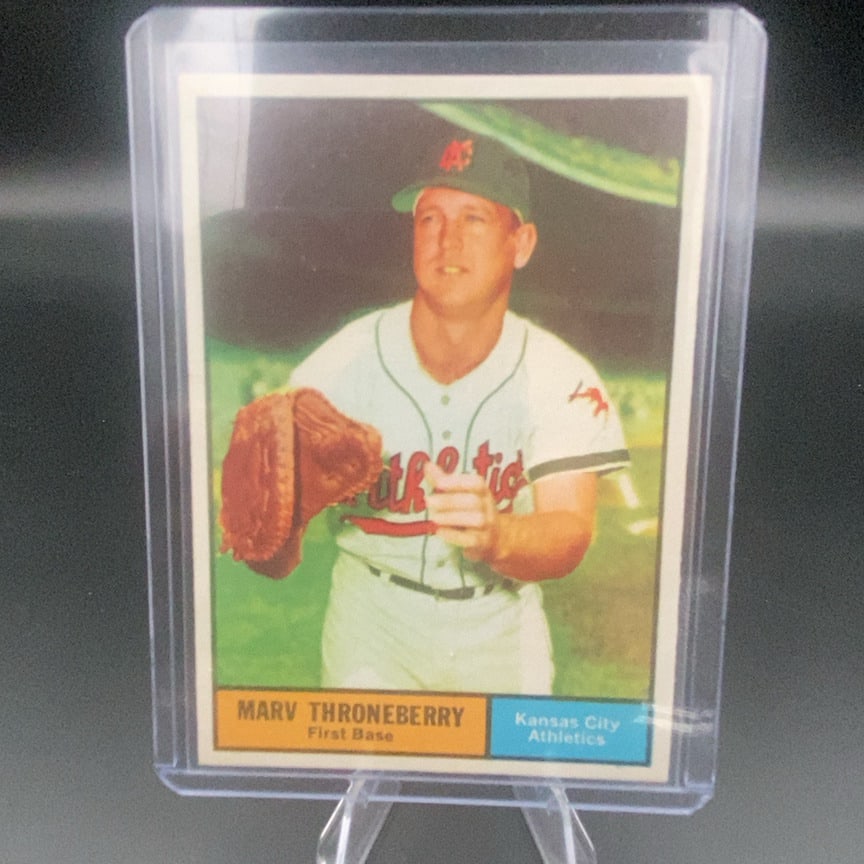 1961 Topps #57 Marv Throneberry baseball card: This is a vintage baseball card featuring Marv Throneberry, who is identified as playing the position of First Base for the Kansas City Athletics. The card is protected in a hard plastic top loader