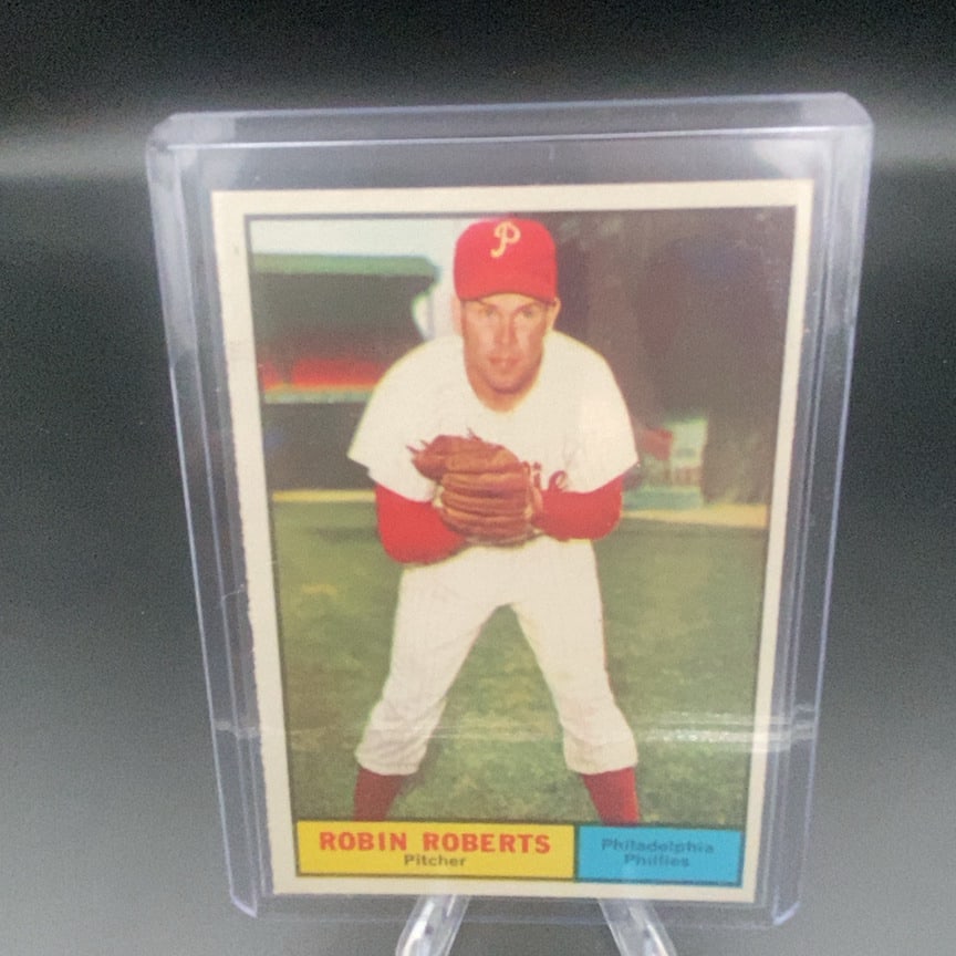 1961 Topps #20 Robin Roberts baseball card: This trading card features Robin Roberts in his Philadelphia Phillies uniform. It captures the pitcher in a classic pose on the field. The card is preserved in a clear protective case.