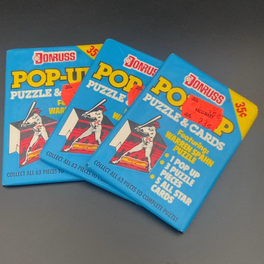 Donruss Pop-Up Puzzle & Cards: This is a collection of three unopened wax packs of Donruss Pop-Up Puzzle & Cards. The packaging features a Warren Spahn puzzle and notes that each pack contains one pop-up, three puzzle pieces, and