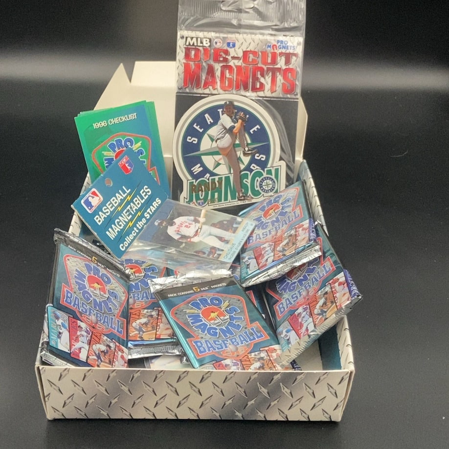 1996 Pro Magnets Baseball Collection: This is a collection of 1996 Pro Magnets baseball memorabilia, featuring a box filled with sealed magnet packs and a loose die-cut magnet of Randy Johnson. The set includes a checklist and several
