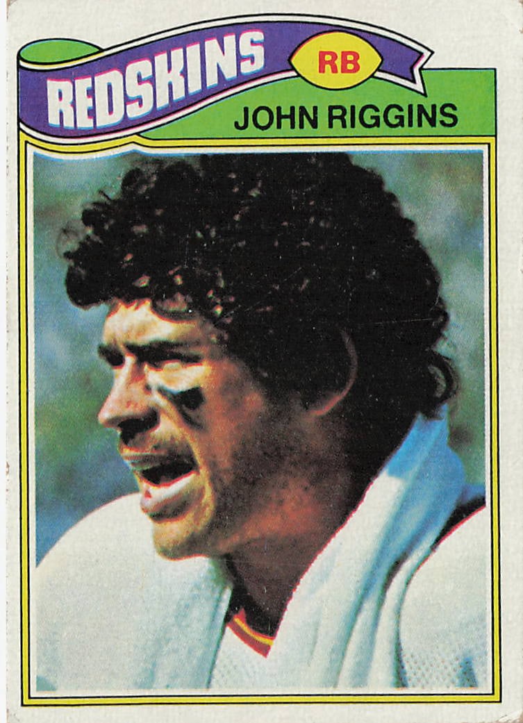 1977 Topps John Riggins #55 football trading card: This is a 1977 Topps football trading card featuring John Riggins of the Washington Redskins. The card highlights Riggins during his NFL career as a powerful running back and features the classic