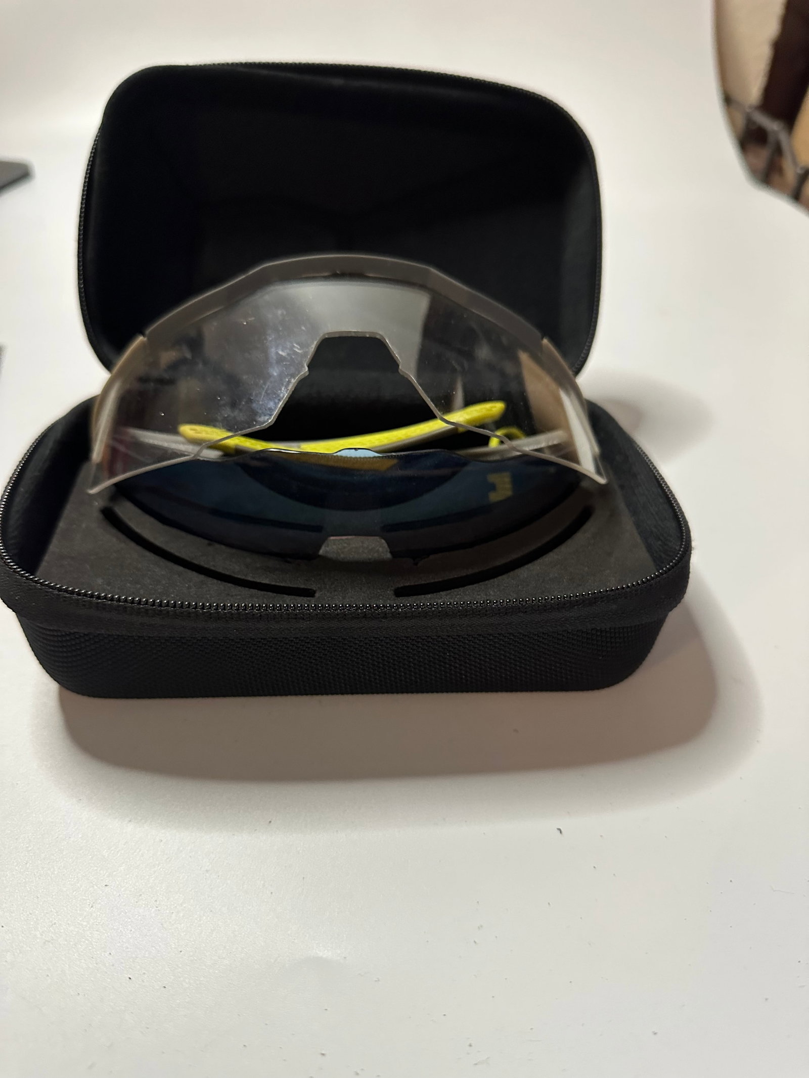 100% Sunglasses with Case: This item is a pair of 100% Clear Speed Glasses stored inside a protective black zippered hard case. The sunglasses feature a prominent shield-style lens and distinct yellow accents on the frame