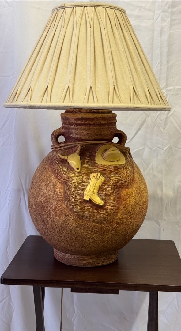 Vintage Southwestern Lamp: Southwestern Style ceramic lamp with raised cowboy motifs. Pleated conical fabric shade.These are part of the estate sale and we do not have a COA. All lots offered in our auctions are sold strictly o