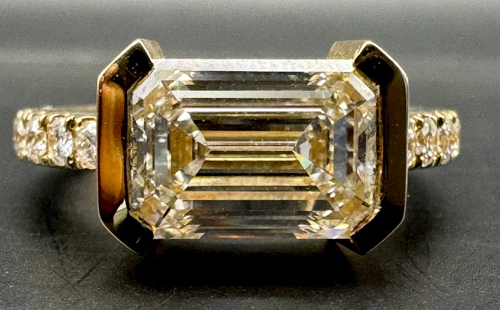 14K YELLOW GOLD EMERALD CUT LAB DIAMOND RING 3.66CT: 14K yellow gold ring featuring a 3.00ct emerald cut lab-grown diamond center stone, F color, VS1 clarity, set in bezel setting. Accompanied by 0.66ct round brilliant cut lab-grown diamond side stones,