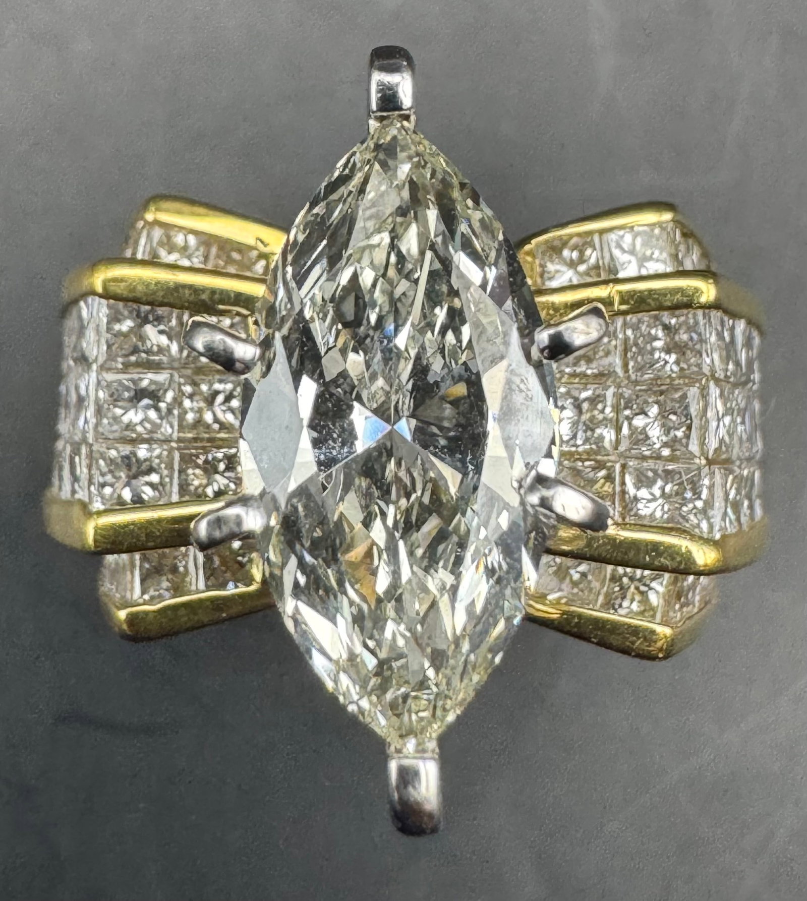 18K YELLOW GOLD MARQUISE PRINCESS CUT EARTH-MINED DIAMOND RING 4.83CT: 18K yellow gold ring featuring a 2.03ct marquise cut earth-mined diamond center stone, L/M color, VS1 clarity, set in 6 prong setting. Side stones feature 2.80ct princess cut earth-mined diamonds, F/G