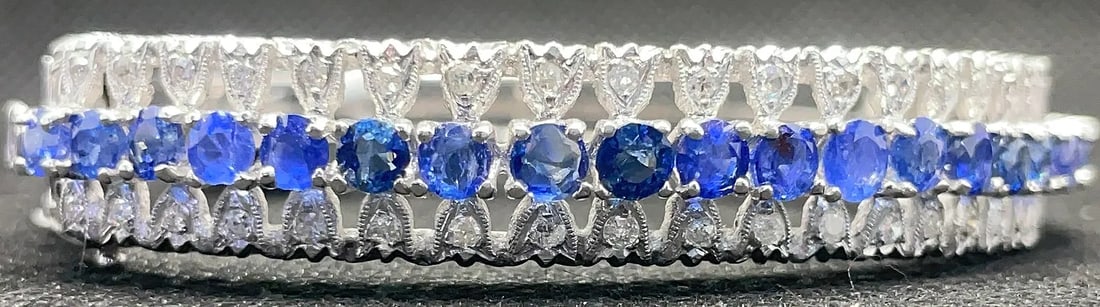 14K WHITE GOLD SAPPHIRE DIAMOND PAVE BANGLE 9.00CT SAPPHIRE 0.50CT DIAMOND: 14K white gold bangle featuring 9.00ct round cut sapphires and 0.50ct round brilliant cut diamonds in pave setting. High polish finish. Total bangle weight 27.0 grams. Stamped 14K. New condition. Item