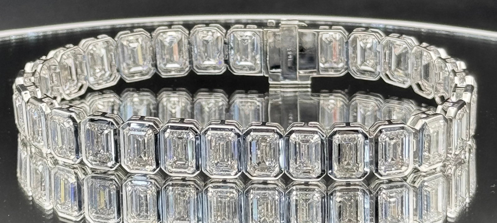 31.87CTW EMERALD-CUT LAB DIAMOND BEZEL TENNIS BRACELET 14K WHITE GOLD: An elite 14K white gold tennis bracelet featuring 29 stunning emerald-cut lab-grown diamonds totaling an impressive 31.87 carats. These diamonds feature a high-tier E-F color and VS clarity, offering 