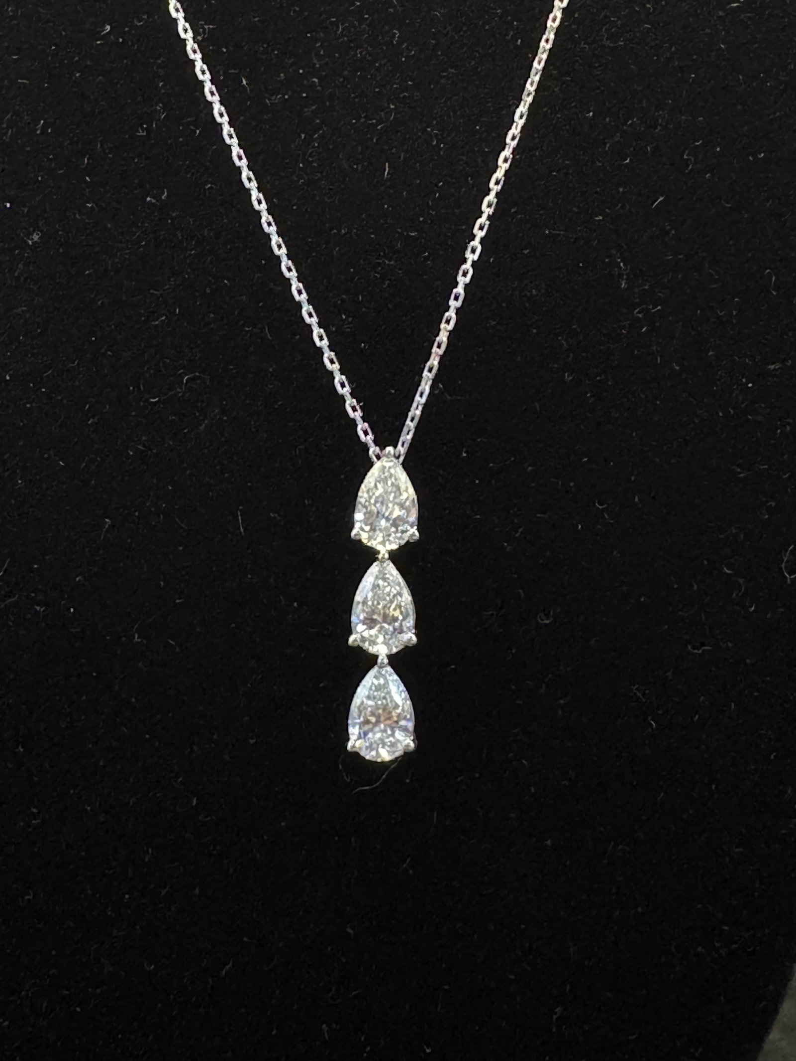 3-Stone Lab-Grown Pear Diamond Pendant | 14k White Gold | Silver Chain: A sophisticated blend of high-end materials. This tiered pendant features three cascading lab-grown pear-cut diamonds, expertly set in solid 14k white gold. The vertical three-stone configuration is d