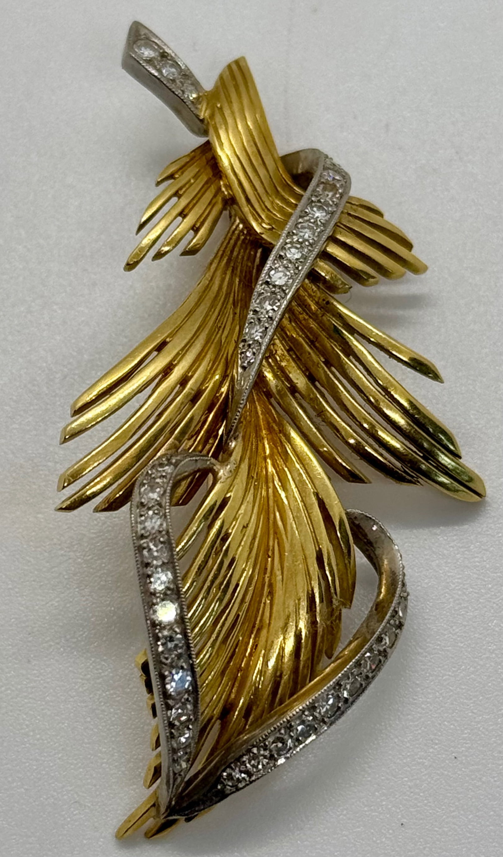 Vintage 18k Yellow Gold & Diamond "Feather" Statement Brooch: This exquisite brooch is masterfully crafted in solid 18k yellow gold, featuring a dynamic "feather" or "leaf" motif with intricate textured ribbing. The piece is elegantly entwined with ribbons of so
