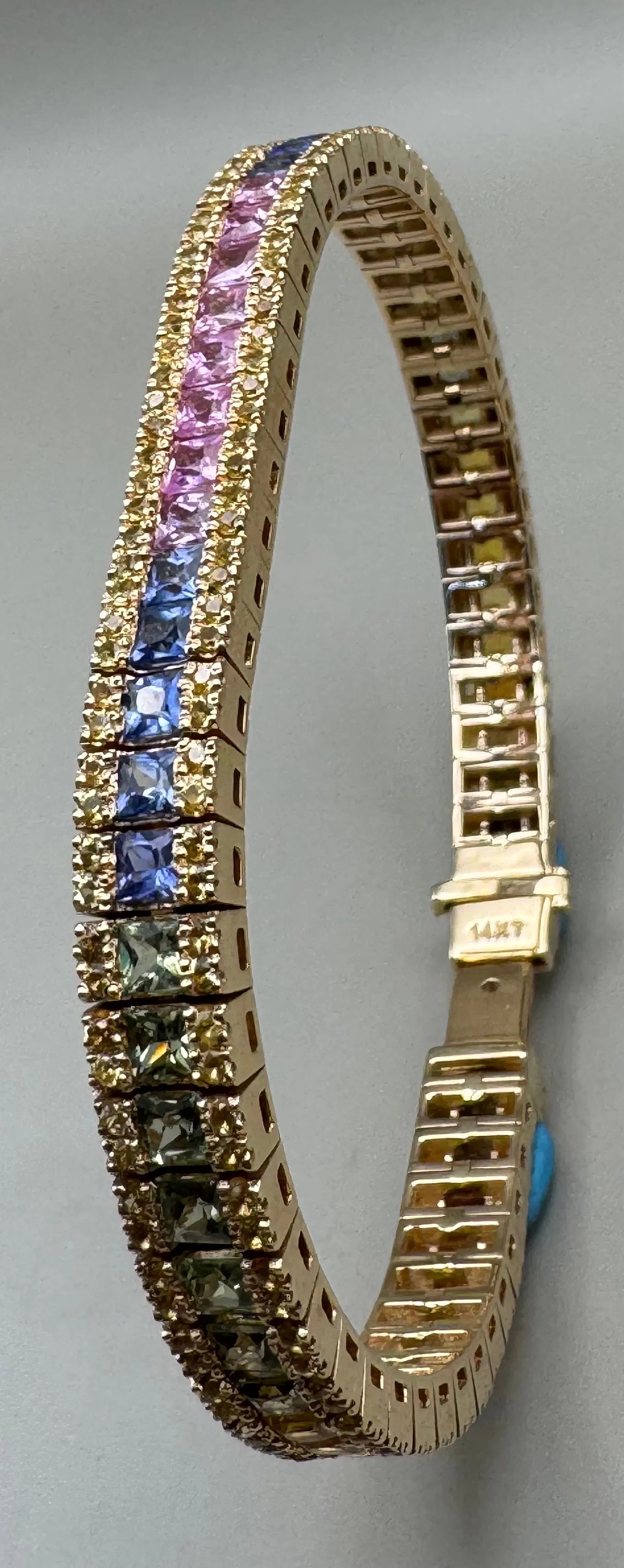 14K YELLOW GOLD MULTI-COLOR SAPPHIRE TENNIS BRACELET 9.00CT: 14K yellow gold sapphire tennis bracelet featuring 58 princess cut and 232 round brilliant cut natural earth-mined multi-colored sapphires totaling 9.00ct. Princess cut sapphires set in channel settin