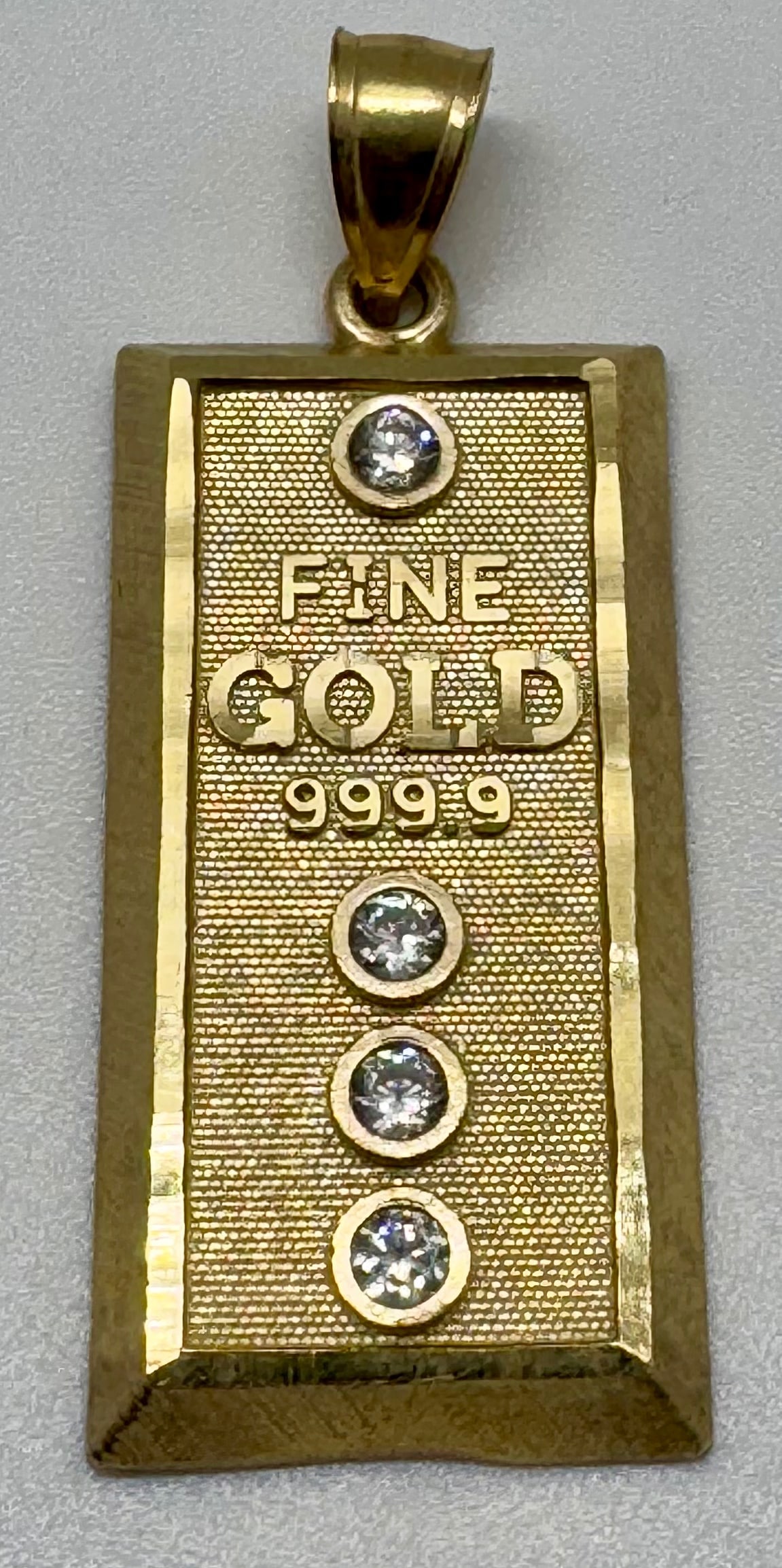 10K YELLOW GOLD "FINE GOLD" DESIGN PENDANT (3.6G): This stunning statement pendant is masterfully crafted in 10K yellow gold, showcasing a beautifully intricate and polished design. Measuring a significant 1.6 inches in length, this piece offers a bol