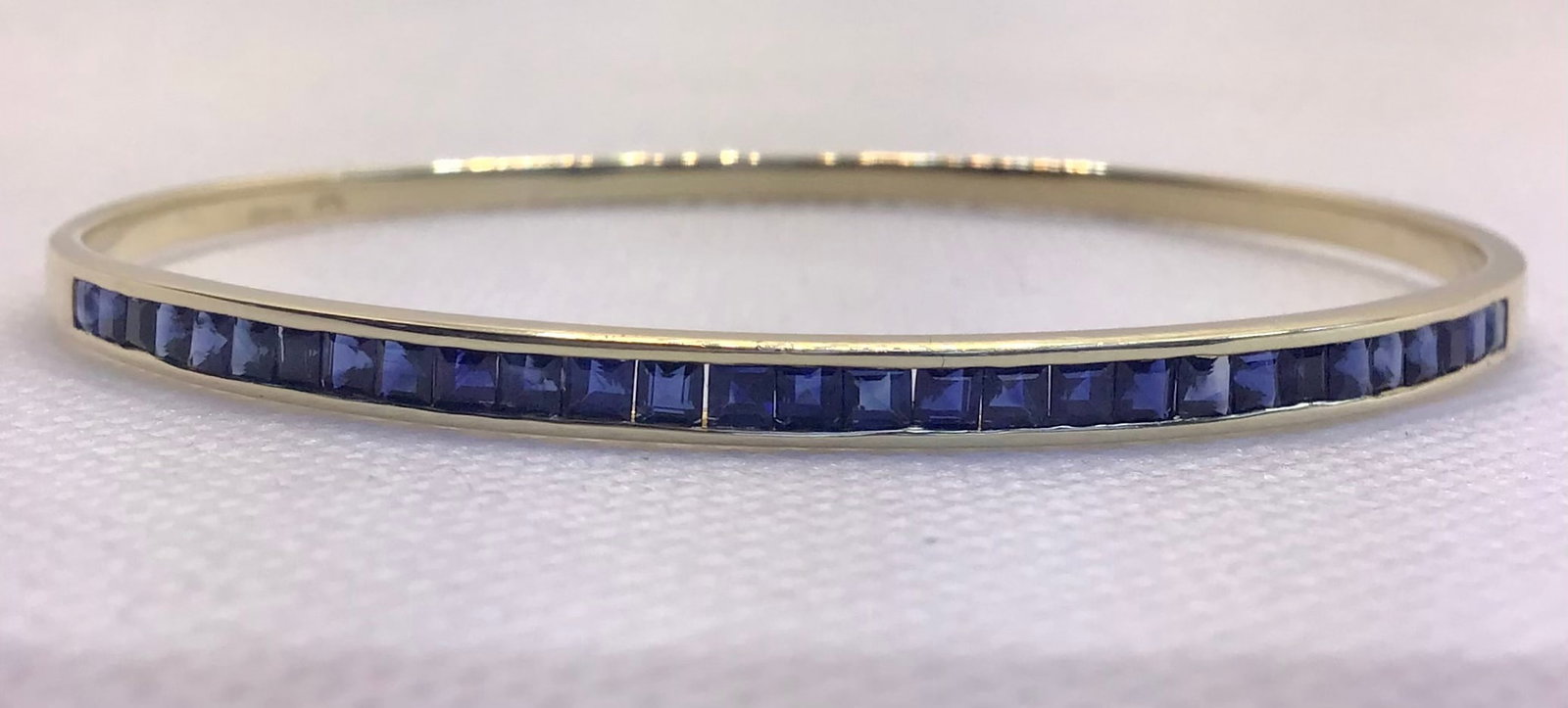 14k Yellow Gold 2.00ctw Invisible-Set Princess-Cut Sapphire Bangle (9.4g): This stunning slip-on bangle bracelet is the ultimate statement piece for holiday parties and high-profile events. Expertly handcrafted in solid 14k yellow gold, the bracelet features 2.00 carats tota