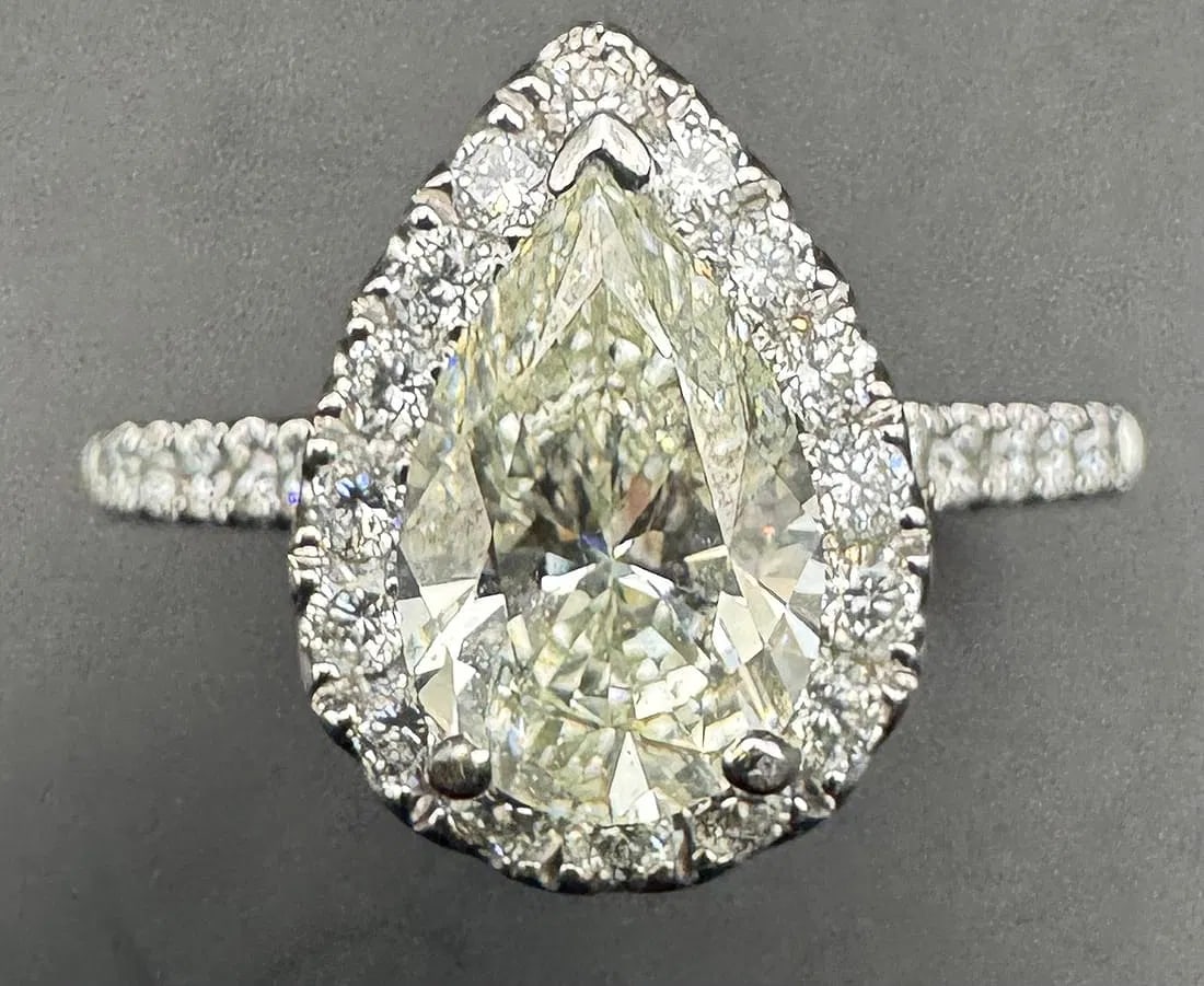 18K WHITE GOLD PEAR CUT DIAMOND RING 2.10CT: 18K white gold ring featuring a 1.35ct pear cut earth-mined diamond center stone, J/K color, VS1 clarity, set in 3 prong setting. Side stones feature 0.75ct round brilliant cut earth-mined diamonds, G