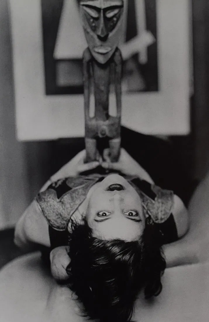 MAN RAY (1890-1976): African sculpture on lying woman, Printed in colors mounted on archival board 10 1/2" x 7"